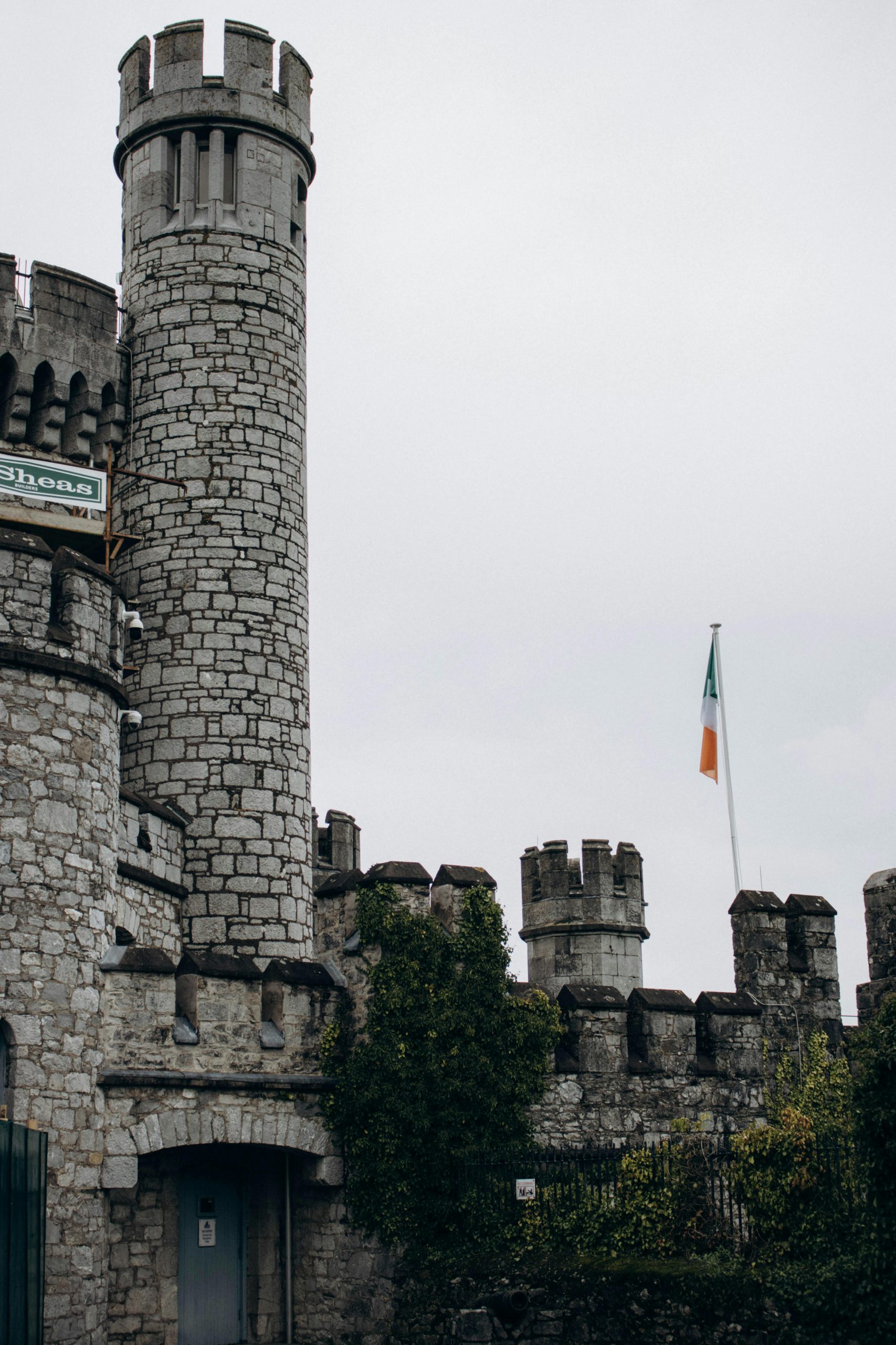 Scenic view of a historic stone castle tower with Irish flag waving in Cork, Ireland.