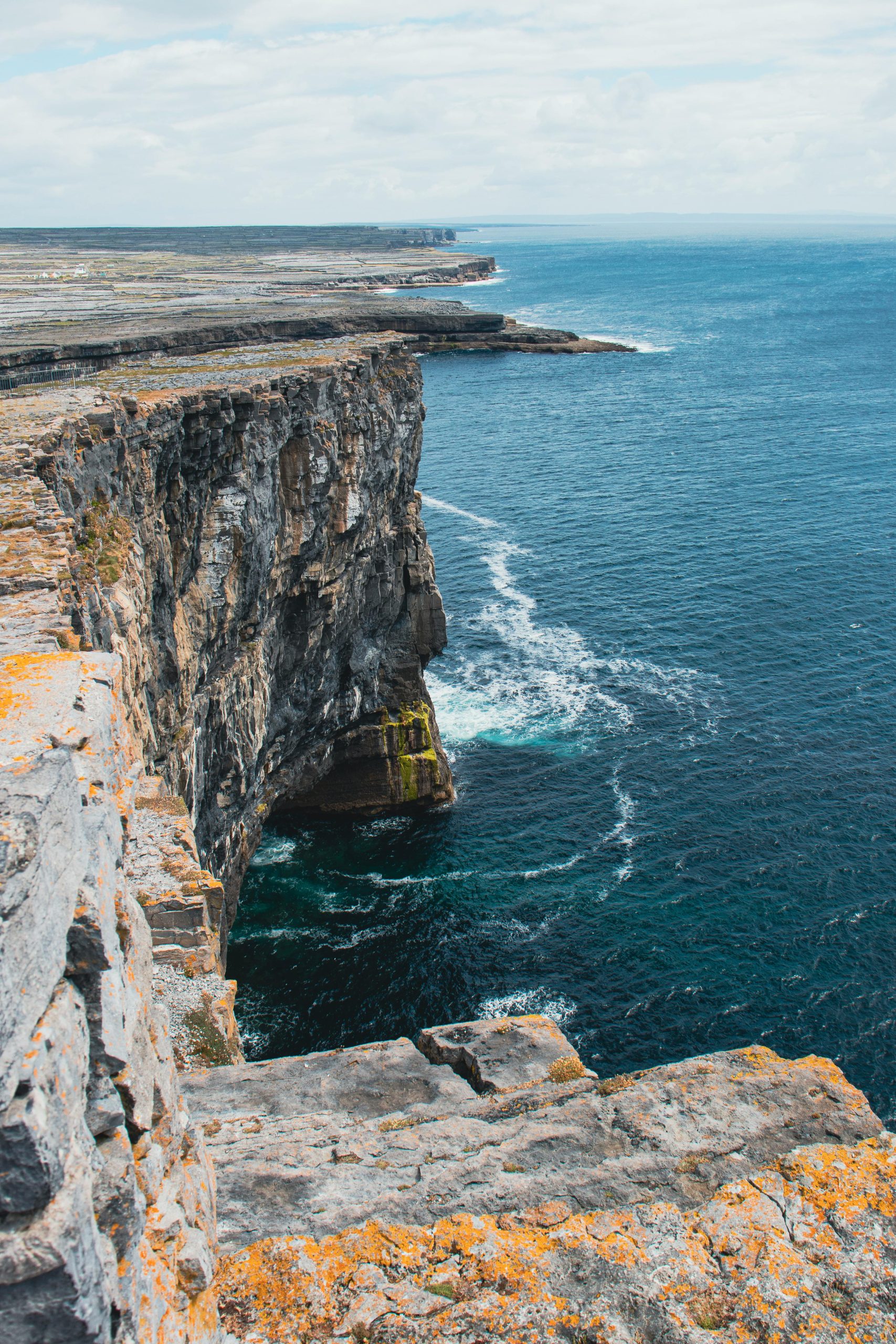 Stunning view of Inishmore cliffs with Atlantic Ocean waves crashing against the rugged coastline.