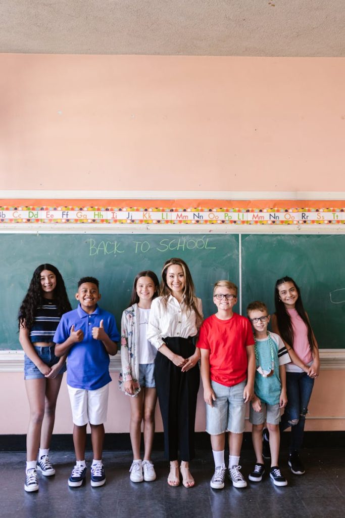 A diverse group of smiling students posing with their teacher in a cheerful classroom setting, marking the first day back to school.